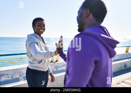 Mann und Frau tragen Sportkleidung mit hohen fünf Händen am Meer angehoben Stockfoto