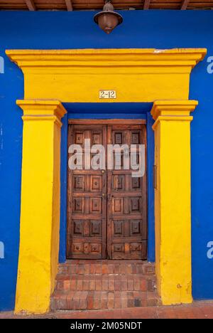 Woodem-Tür in einem gelbblauen Gebäude, La Candelaria, Bogotá, Kolumbien Stockfoto