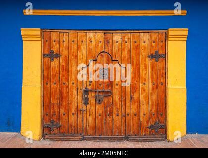 Große Holztür mit Schließfach in einem blau-gelben Gebäude. La Candelaria, Bogotá, Kolumbien Stockfoto