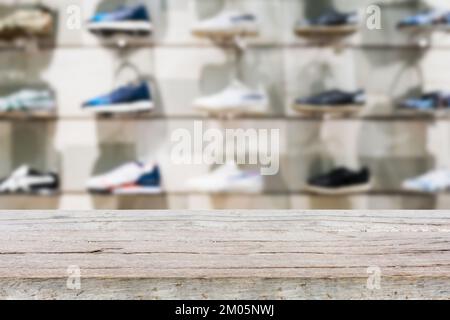 Tischplatte aus Holz mit Schuhen auf den Regalen in den Schuhen speichert einen unscharfen Hintergrund, um die Produktpräsentation zu gestalten Stockfoto