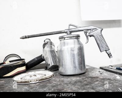 Lackierpistole auf Holztisch im Kfz-Reparaturzentrum Stockfoto