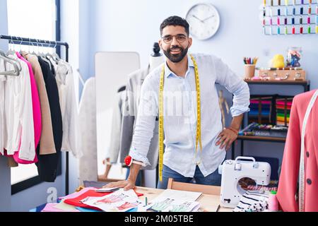 Ein junger arabischer Schneider, der selbstbewusst im Schneiderladen steht Stockfoto