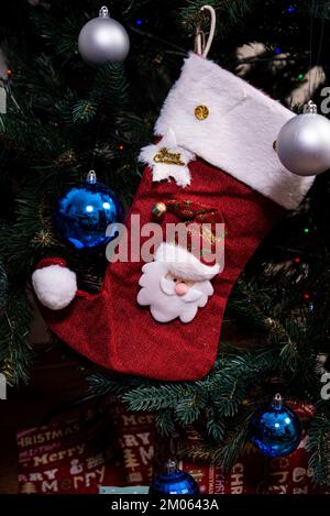 Weihnachtsstrumpf. Rote Socke mit Schneeflocken als Weihnachtsgeschenke, die am Weihnachtsbaum hängen. Winterurlaub Dekoration Stockfoto