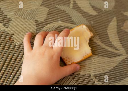 Kinderhände und Kekse mit Butter auf dem Tisch Stockfoto