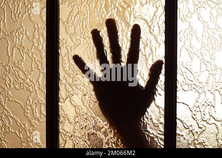 Die Hand einer Frau in einer Tür in einem dunklen Raum Stockfoto