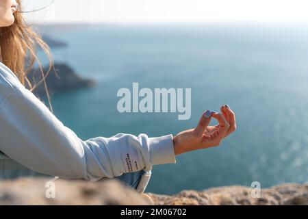 Yoga, Geste und gesundes Lifestyle-Konzept - Hand der meditierenden Yoga-Frau zeigt Gyan Mudra über Meer Sonnenuntergang Hintergrund Stockfoto