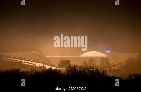 Leipzig, Deutschland. 04.. Dezember 2022. Der nächtliche Nebel strahlt das gelbe Licht aus dem Innern der Red Bull Arena in Leipzig aus. Die Woche endet mit kaltem und nassem Wetter. Kredit: Hendrik Schmidt/dpa/Alamy Live News Stockfoto