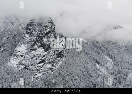 Schnee auf der Felswand des Mount Si in den Washington Cascade Mountains, während niedrige Wolken den Gipfel verdecken Stockfoto