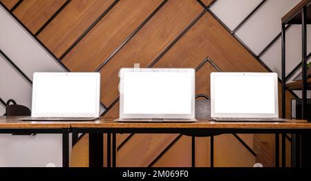 Mehrere Modelle von Laptopbildschirmen auf einem Holzschreibtisch in einem modernen Büro. Multi-Display, Monitormodell von Computerdisplays. Hochwertiges Foto Stockfoto