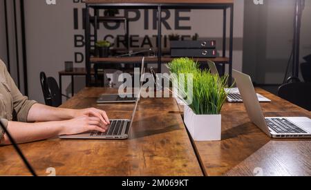 Nachtarbeitskonzept. Hand, Laptop auf Büroschreibtisch in der Nacht. Allein in moderner Inneneinrichtung arbeiten. Hochwertiges Foto Stockfoto