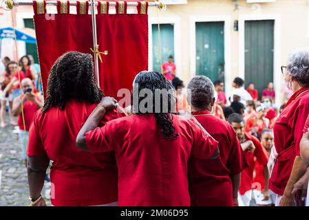 Salvador, Bahia, Brasilien - 04. Dezember 2022: Anhänger von Santa Barbara, die während der Messe im Largo do Pelourinho in der Stadt Salvador rot gekleidet waren. Stockfoto