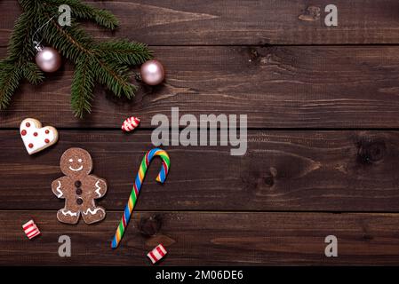 Weihnachtskomposition mit Lebkeksen, Tannenzweigen und weihnachtsdekor auf Holztisch mit Platz für Text. Stockfoto