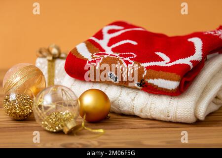 Warme Weihnachtspullover. Winterurlaub Strickpullover mit Muster auf Holzhintergrund und Weihnachtsdekorationen. Ein Haufen warmer Weihnachten Stockfoto