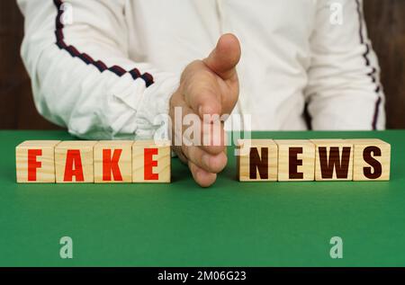 Geschäftskonzept. Ein Mann trennt die Würfel mit der Inschrift "FAKE vs NEWS" Stockfoto