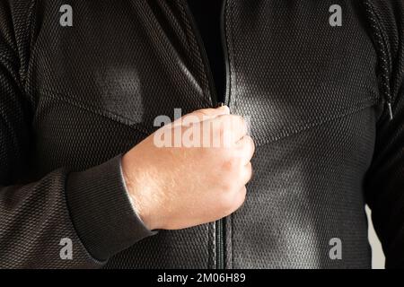 Männliche Hand öffnet den Reißverschluss an einer grauen Sportjacke, Jacke mit Reißverschluss und Schloss Stockfoto