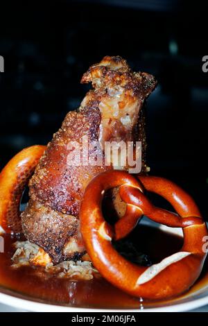 Gebratene knusprige Schweineknöchel mit deutscher Brezel und Soße in Nahaufnahme Stockfoto