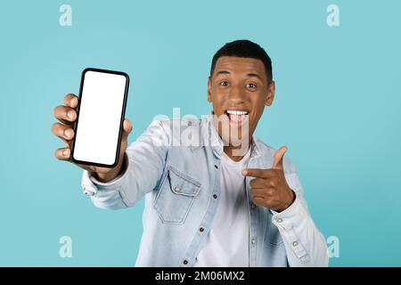 Wow, coole Website. Zufriedener junger afroamerikanischer Kerl, der mit dem Finger auf ein Smartphone zeigt, mit leerem Bildschirm Stockfoto