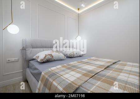 Stilvolles Interieur aus grauem und weißem Schlafzimmer mit komfortablem Bett Stockfoto