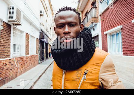 Ein gut aussehender afrikanischer Erwachsener, der mitten auf der Straße steht und ruhig und ernsthaft in die Kamera schaut Stockfoto