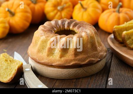 Hausgemachter Kürbiskuchen. Gebackener Kürbiskuchen auf dem Küchentisch. Kürbisse im Hintergrund. Stockfoto