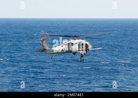 33. Mitglieder der Rettungstruppe heben am 22. November 2022 einen Sanitäter, der der 31. RS zugeteilt wurde, in einen HH-60 Pave Hawk über dem Pazifik. Der 33. RQS führt umfassende Schulungen in verschiedenen Rettungsszenarien durch, um sicherzustellen, dass er auf reale Eventualitäten effektiv reagieren kann. (USA Air Force Photo von Senior Airman Cesar J. Navarro) Stockfoto