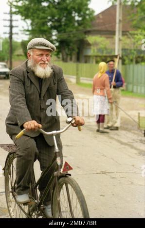 Prahova County, Rumänien, Mai 1990, ein paar Monate nach dem Fall des Kommunismus, ein einheimischer Mann, der in einer Dorfarmut mit dem Fahrrad fährt Stockfoto