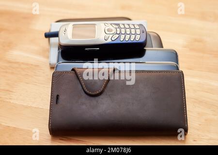 Ein Haufen alter, verbrauchter Handys aus verschiedenen Jahrzehnten, die sich auf dem Tisch stapeln Stockfoto