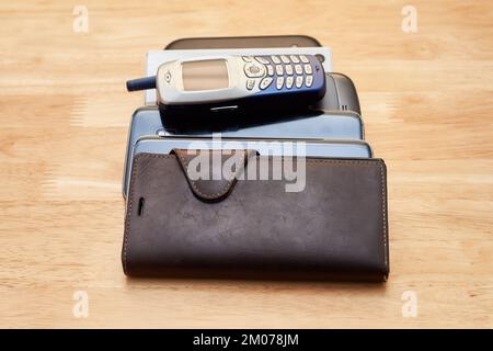 Ein Haufen alter, verbrauchter Handys aus verschiedenen Jahrzehnten, die sich auf dem Tisch stapeln Stockfoto