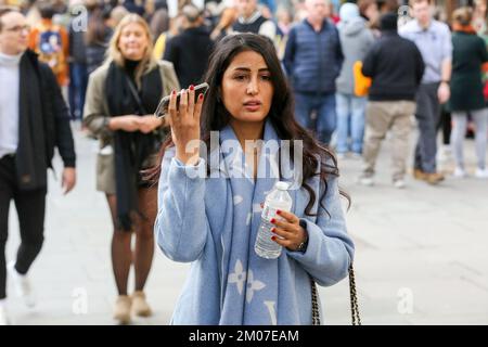 London, Großbritannien. 26.. November 2022. Eine Frau hört auf ihrem Handy, während sie auf der Oxford Street in London spaziert. (Kreditbild: © Dinendra Haria/SOPA Bilder über ZUMA Press Wire) Stockfoto