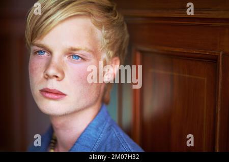 Über das Leben nachdenken. Rücksichtsvoller und attraktiver junger blonder Kerl mit sehr blauen Augen. Stockfoto