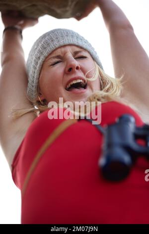 An einem seidenen Faden hängen. Ein junger Kletterer, der von einer Klippe hing und vor Angst schrie. Stockfoto