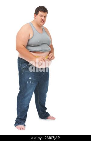 Nicht das Ergebnis, das er wollte. Porträt eines fettleibigen jungen Mannes, der seine Taille mit einem Maßband vor weißem Hintergrund misst. Stockfoto