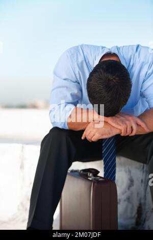 Die Auswirkungen einer stressigen Arbeit zu spüren. Ein verärgerter Geschäftsmann mit Hsi-Kopf unten, der auf seinen Armen mit Kopierraum ruht. Stockfoto