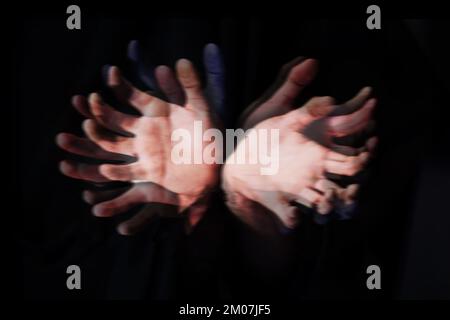 Geisterfinger. Verschwommenes Bild von zwei Händen vor schwarzem Hintergrund. Stockfoto