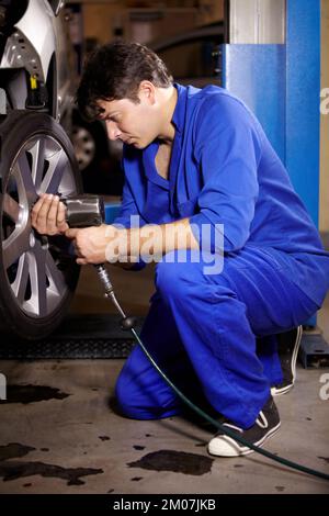 Montage einiger neuer Reifen. Ein Mechaniker, der am Rad eines Autos arbeitet. Stockfoto