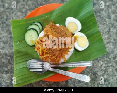 Ein Teller mit pikanter Gewürzsoße mit gebratenen Sardellen auf Bananenblättern Stockfoto