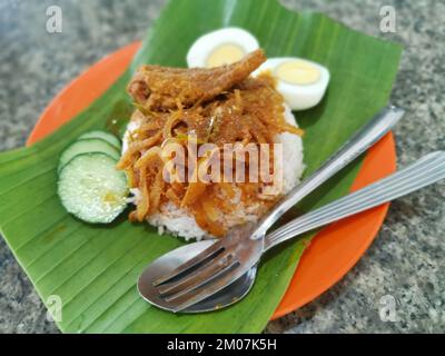 Ein Teller mit pikanter Gewürzsoße mit gebratenen Sardellen auf Bananenblättern Stockfoto