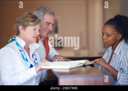 Ich glaube, Sie sind in Zimmer 104. Ein Seniorenpaar hat im Hotel eingecheckt. Stockfoto