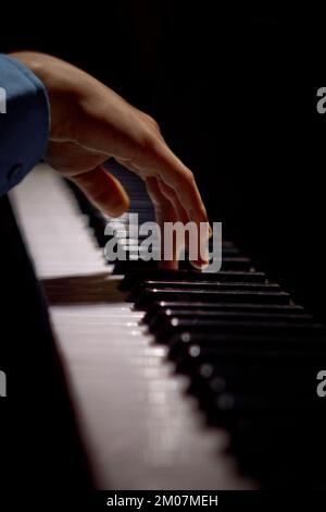 Eine männliche Hand auf dem Klavier. Die Handfläche liegt auf den Tasten und spielt das Tastaturinstrument in der Musikschule. Der Schüler lernt zu spielen. Hände Pianist. bl Stockfoto