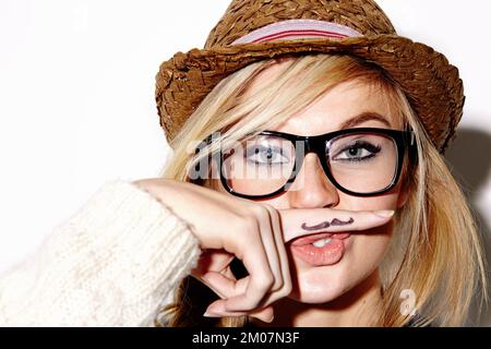 Respektiere den Schnurrbart. Verkürzte Studioaufnahme einer jungen weiblichen Hipsterin mit einem Fingerbart. Stockfoto