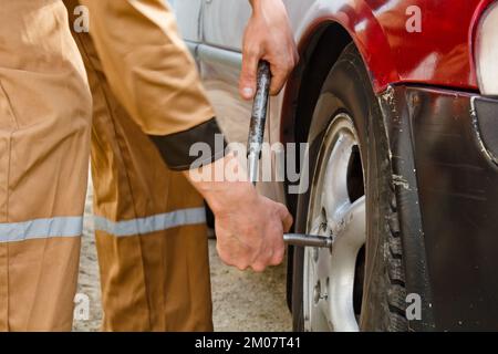 Automechaniker mit Elektroschraubenzieher, der den Reifen auswechselt. Autoservice. Reifen auf Rädern werden von Hand ausgetauscht. Reifenmontagekonzept Stockfoto