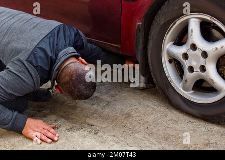 Automechaniker mit Elektroschraubenzieher, der den Reifen auswechselt. Autoservice. Reifen auf Rädern werden von Hand ausgetauscht. Reifenmontagekonzept Stockfoto