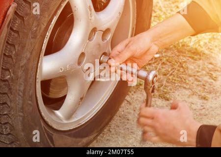 Service-Prozess. Ein Mann hält einen Reifen in der Garage. Wechsel von Winter- und Sommerreifen. Konzept für den saisonalen Reifenwechsel Stockfoto