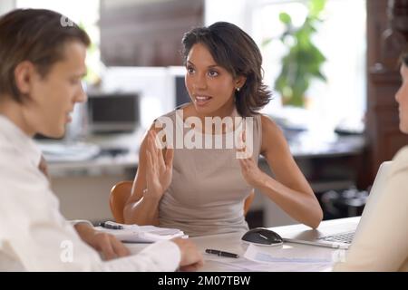 Habe ich mich klar ausgedrückt? Eine Gruppe von Büromitarbeitern, die sich an einem Tisch im Büro unterhalten. Stockfoto