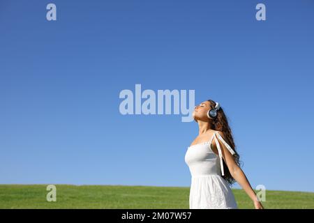 Meditierende Frau, die mit Kopfhörern frische Luft atmet Stockfoto