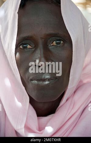 Gesichter Afrikas, Afrikanerin, Bafata, Guinea-Bissau - Frau mit nachdenklichem Gesichtsausdruck und atemberaubendem Kopfkleid Stockfoto