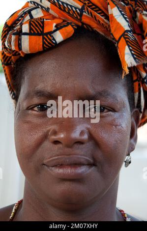 Gesichter Afrikas, Afrikanerin, Bafata, Guinea-Bissau - Frau mit nachdenklichem Gesichtsausdruck und hübschem Kopfkleid Stockfoto