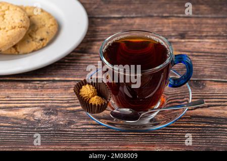 Schwarzer türkischer Tee in Glasbecher mit Shortbread auf Holztisch Stockfoto