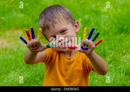 Kinderhände in den Farben des Sommers, ein Lächeln auf der Hand des Jungen. Selektiver Fokus Stockfoto