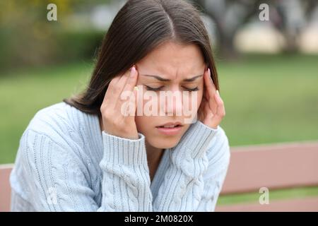 Teenager, die Kopfschmerzen haben und sich im Park beschweren Stockfoto